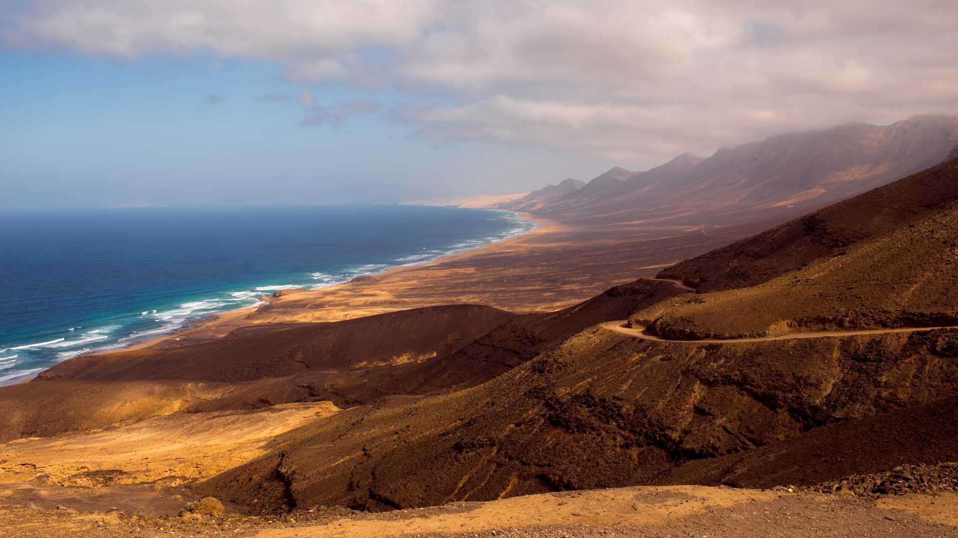 Panoramisch uitzicht op het gouden zand van Cofete Beach en de Atlantische Oceaan, omlijst door de bergen van Fuerteventura.
