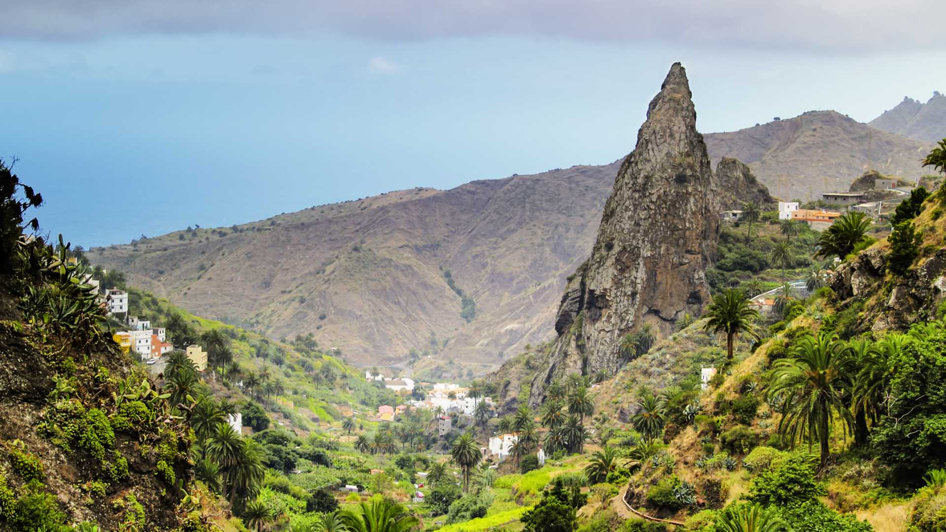 라 고메라의 아름다운 에르미구아의 전경으로, 울창한 녹지, 험준한 산, 독특한 암석 지형이 특징입니다.