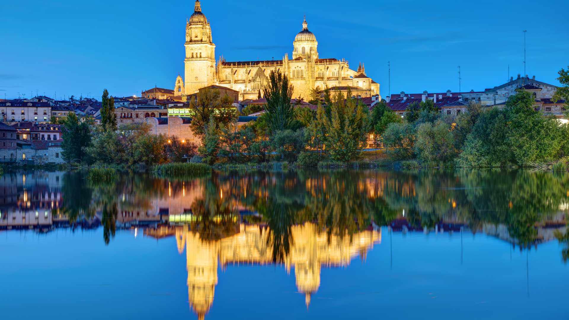 De verlichte kathedraal van Salamanca weerspiegelt in de schemering in het kalme water van de rivier Tormes.
