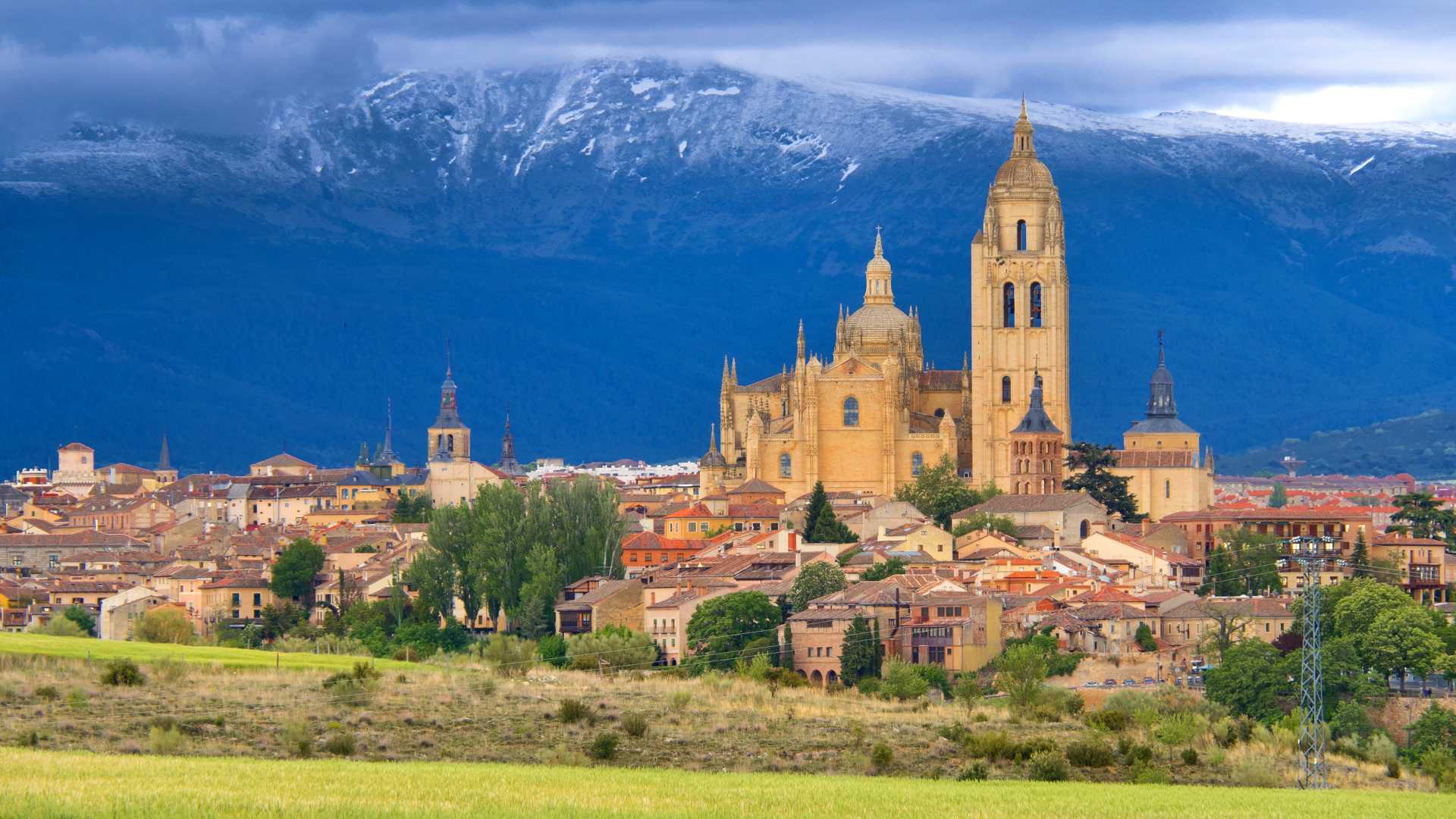 De kathedraal en het stadsbeeld van Segovia tegen de achtergrond van de besneeuwde Guadarrama bergen.