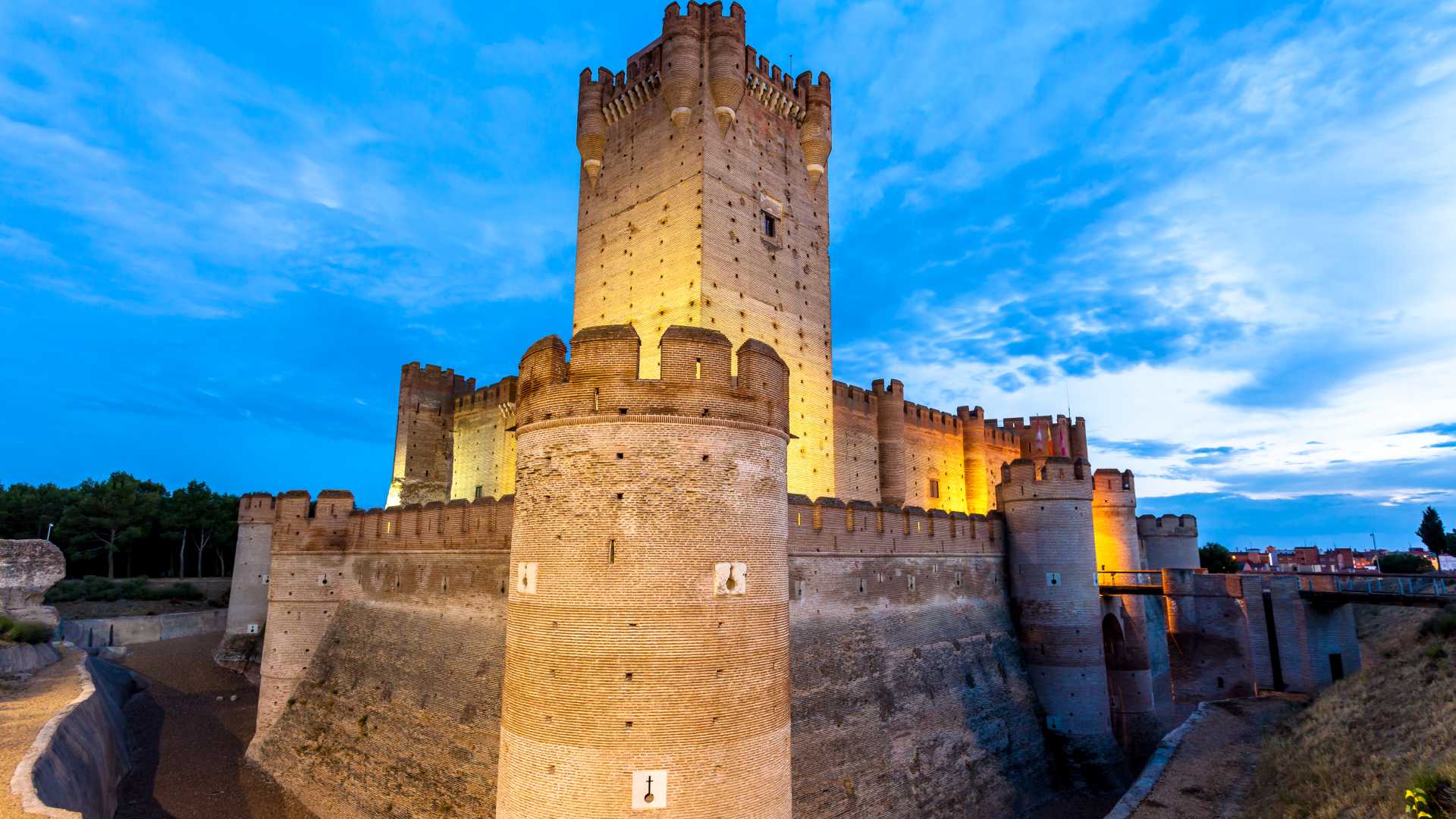 Kasteel van La Mota, een verlicht middeleeuws fort in Medina del Campo, staat tegen een schemerhemel.