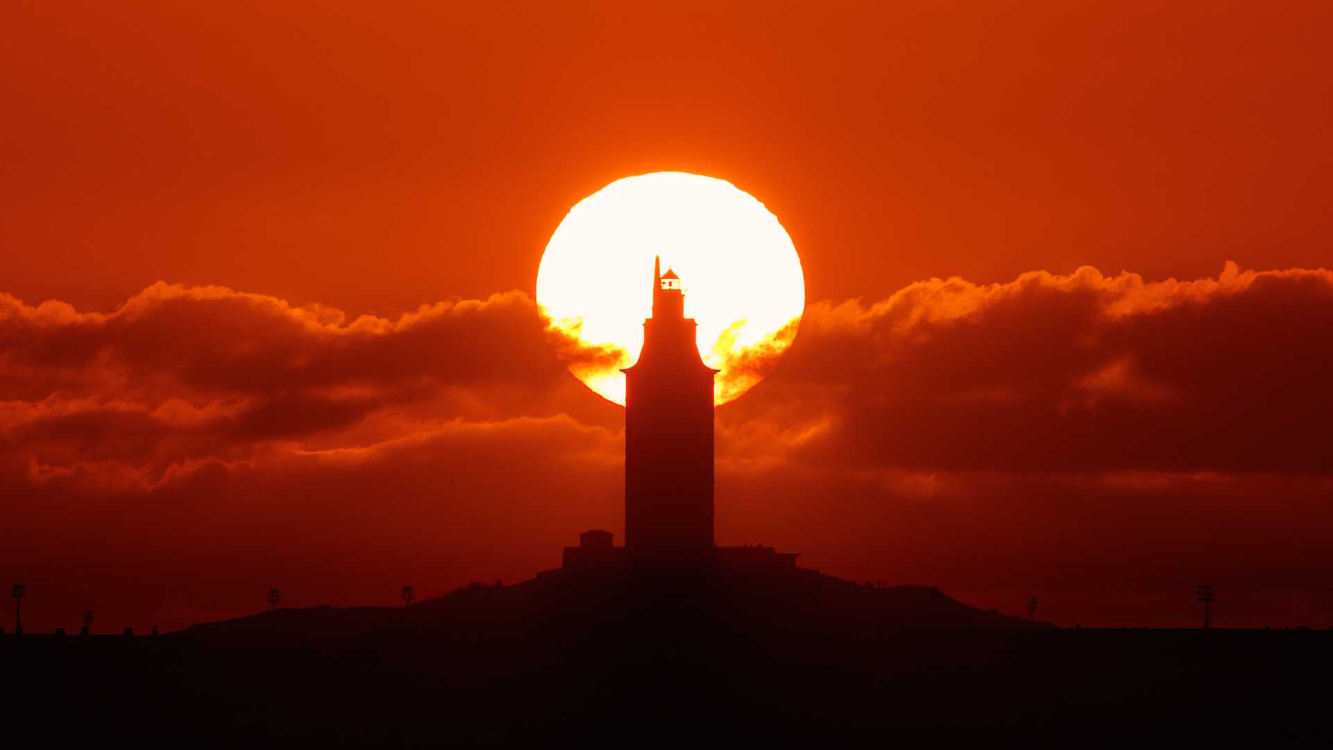 Silhouet van de Toren van Hercules in A Coruña tegen een levendige zonsondergang.