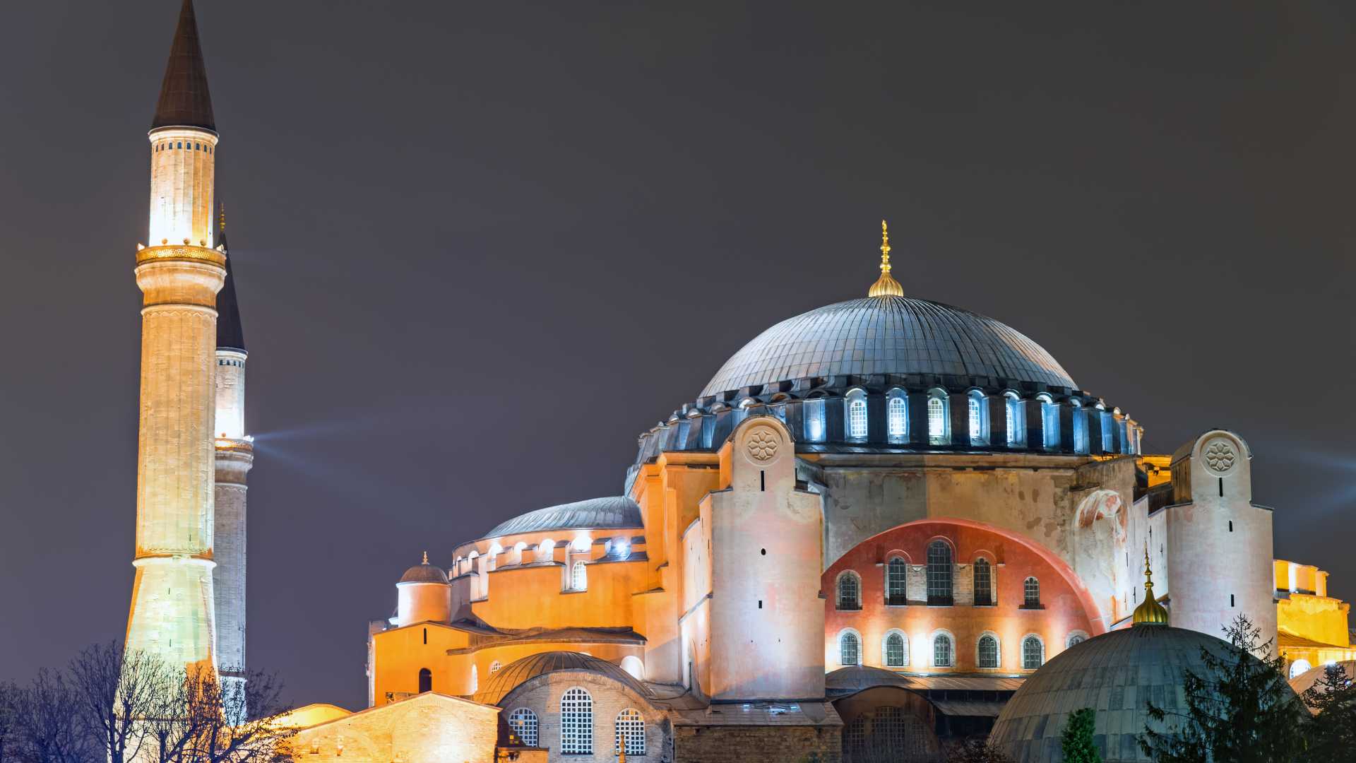 La Hagia Sophia iluminada de noche en Estambul, mostrando su icónica cúpula y minarete contra un cielo oscuro.