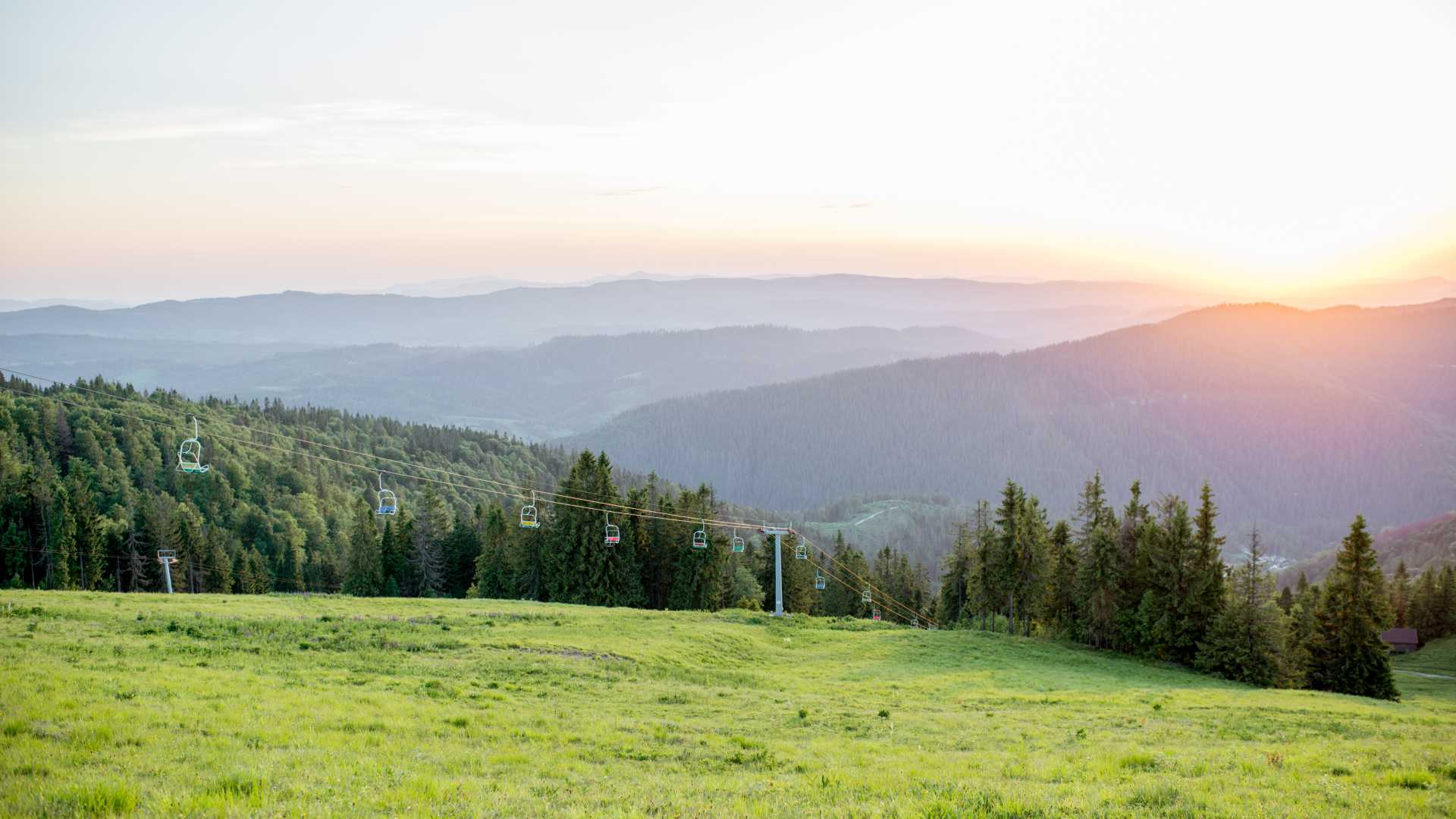 Coucher de soleil sur les Carpates verdoyantes près de Slavske, en Ukraine, avec des forêts et des remontées mécaniques.